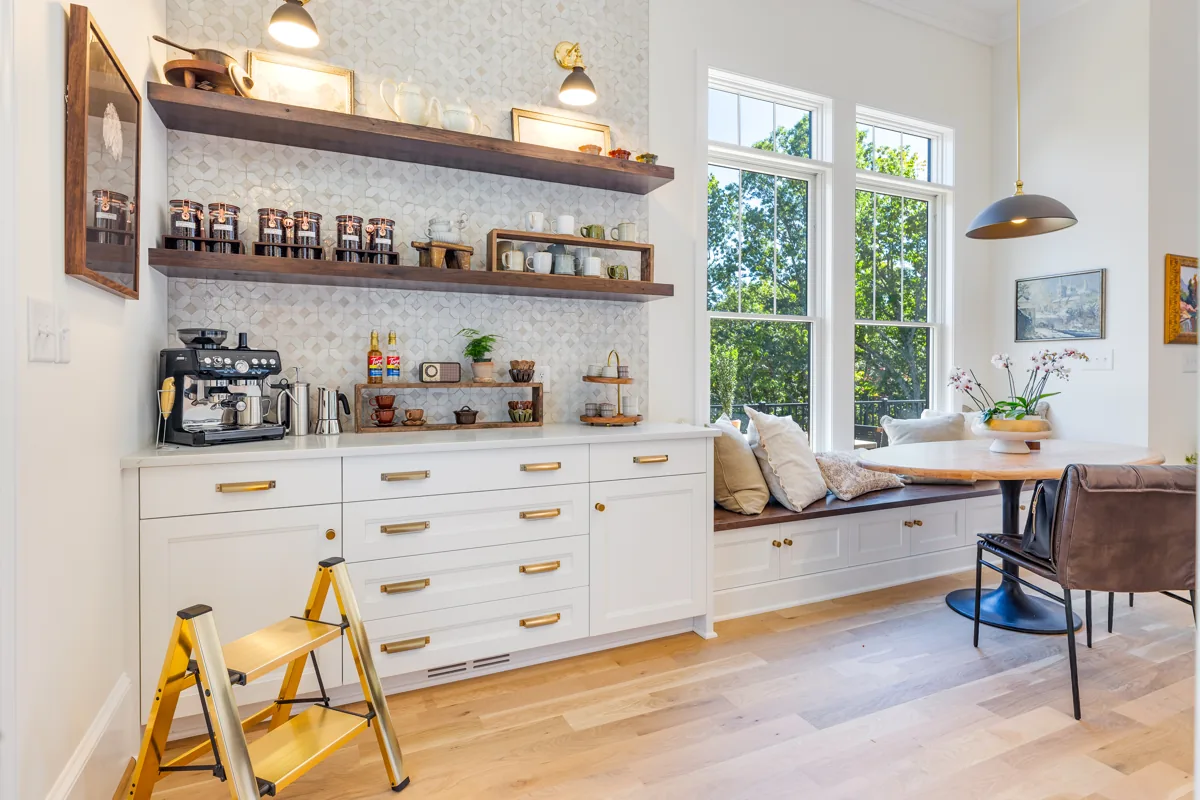 Wood display shelves and white drawers next to a sunny built-in dining nook.