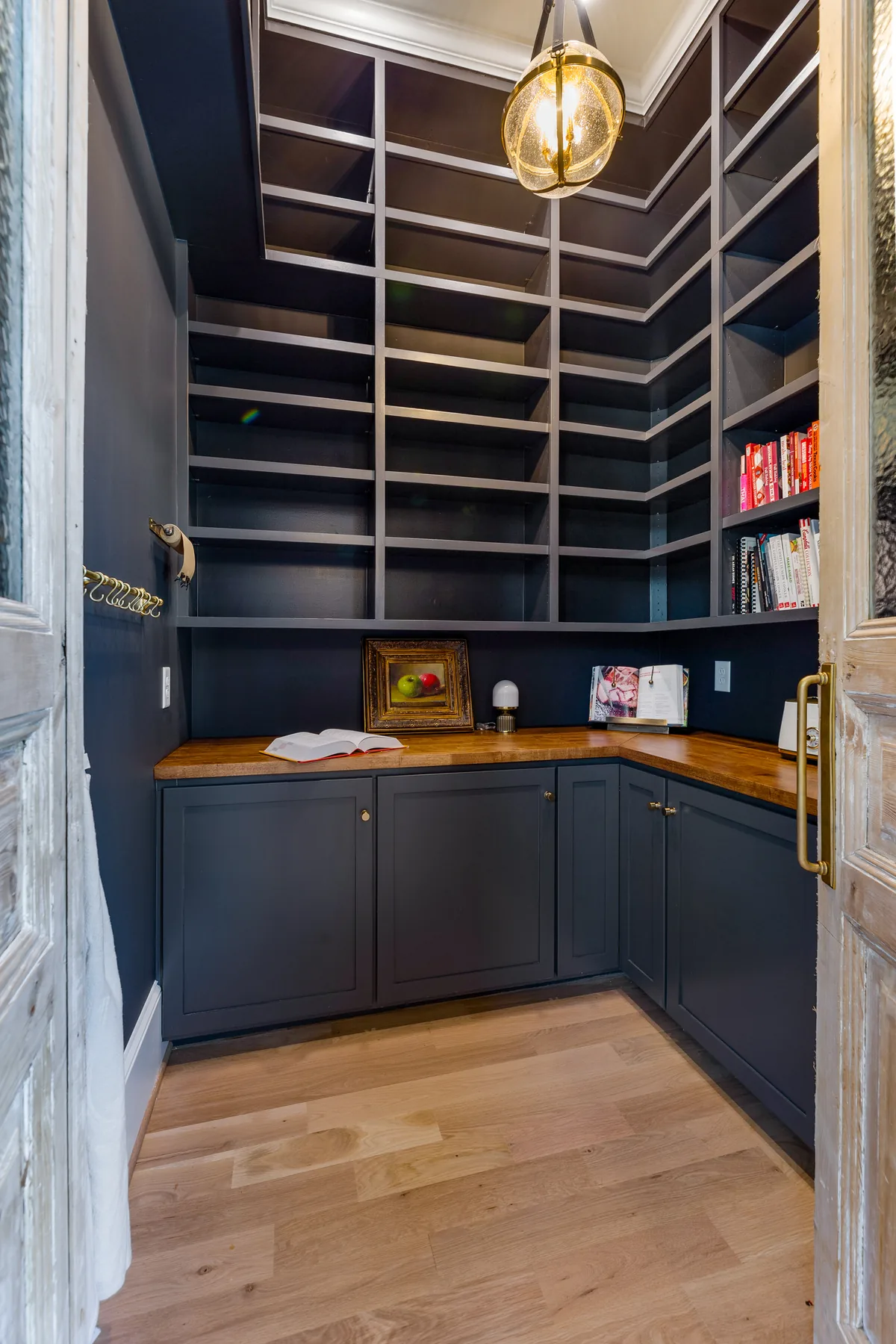 Dark cabinetry and open shelving with warm wood counters and brass accents.