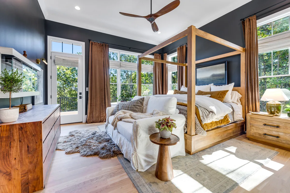 Hunting Hills primary bedroom with a wood canopy bed, charcoal walls, and warm layered textiles.
